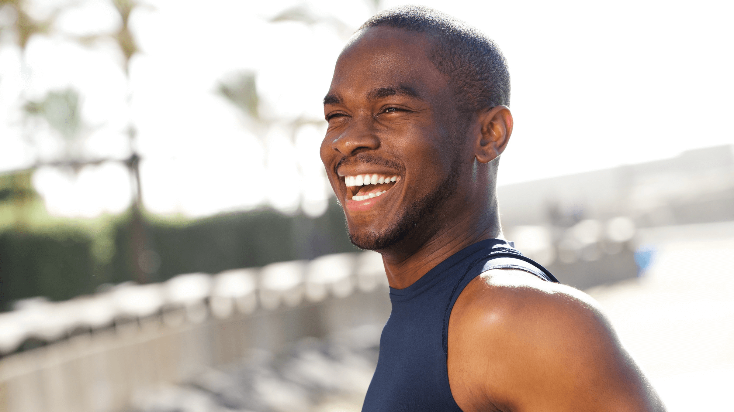 man in tank top smiling outsid